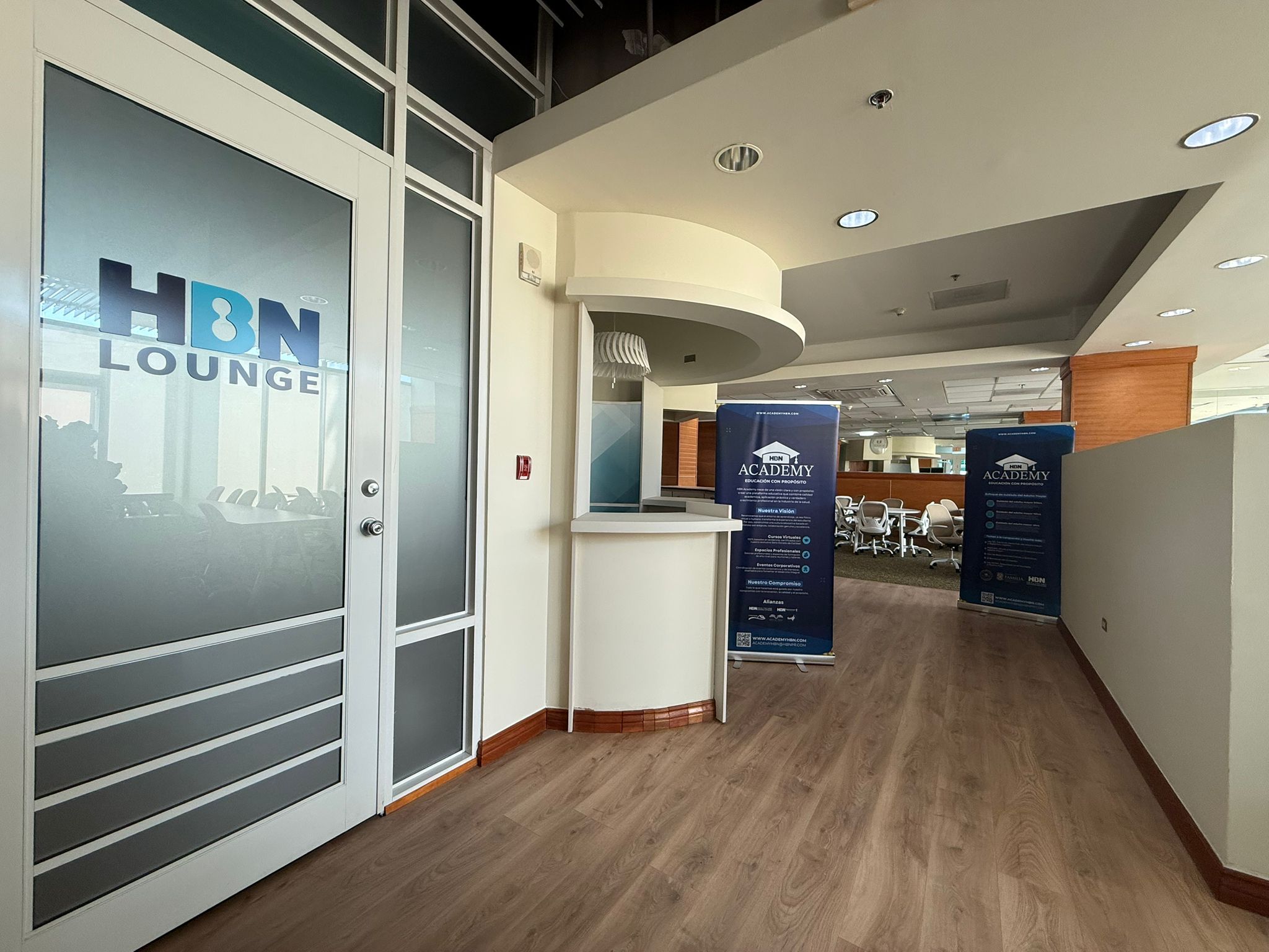 Entrada principal de HBN Lounge con recepcion y banners de HBN Academy