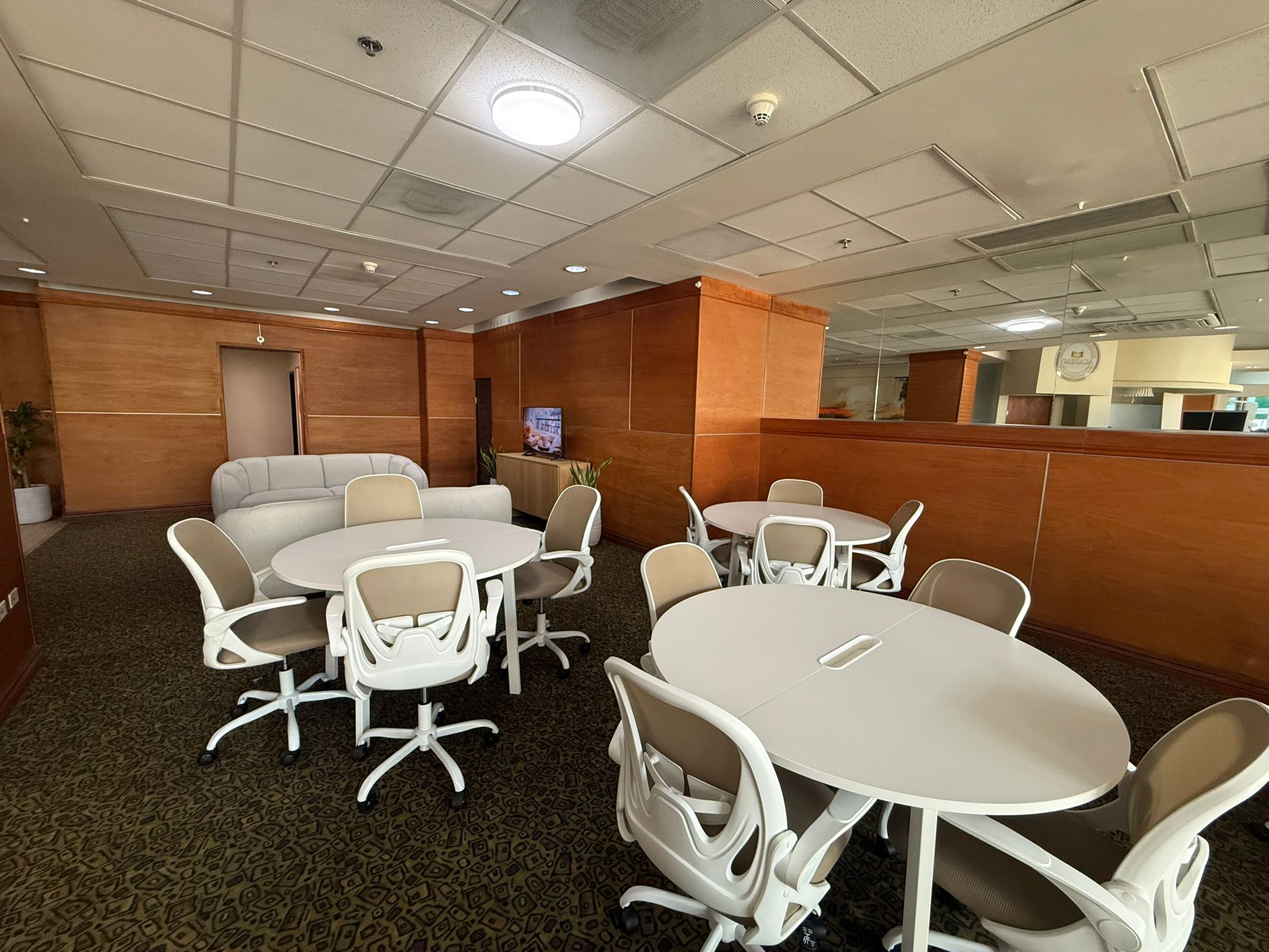 Sala de reuniones con disposicion circular, sofa lounge y pantalla TV